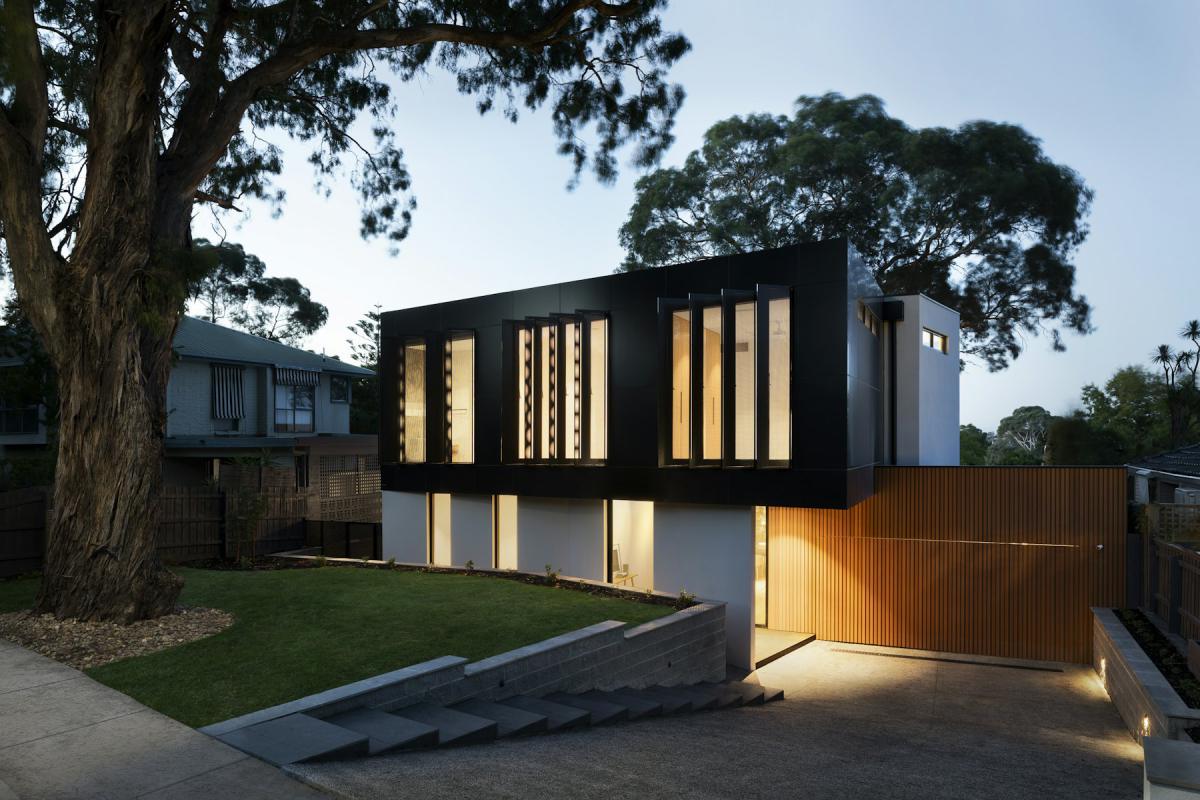 Contemporary home facade glowing with interior lights in the evening