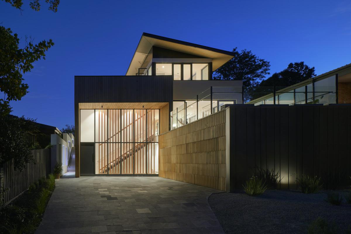 Villa exterior at night with timber screens and illuminated entrance Villa exterior at night with timber screens and illuminated entrance